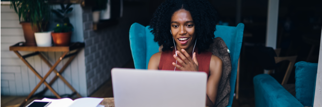 A woman with a surprised expression engaging in a video call on her laptop at home.